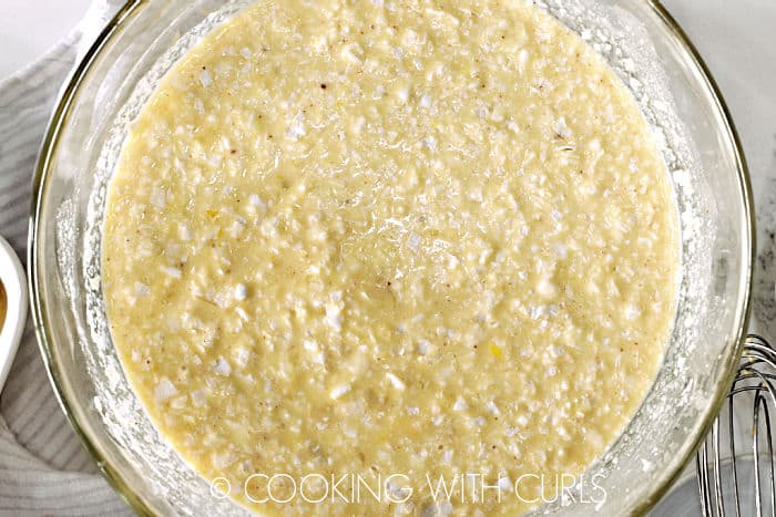 Coconut flakes and pineapple chunks added to the remaining custard mixture in a large glass bowl. 