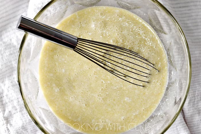 Coconut milk, melted butter, brown sugar, nutmeg, eggs and pineapple juice mixed together in a large glass bowl with a wire whisk. 