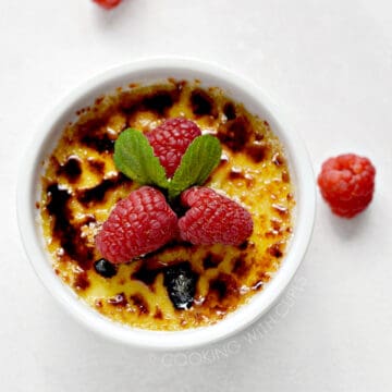 Instant Pot Creme Brulee in a small white ramekin topped with fresh raspberries.