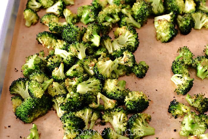 Oven Roasted Broccoli florets on a parchment lined baking sheet. 