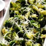 Oven Roasted Broccoli in a white, rectangle platter topped with grated Parmesan.