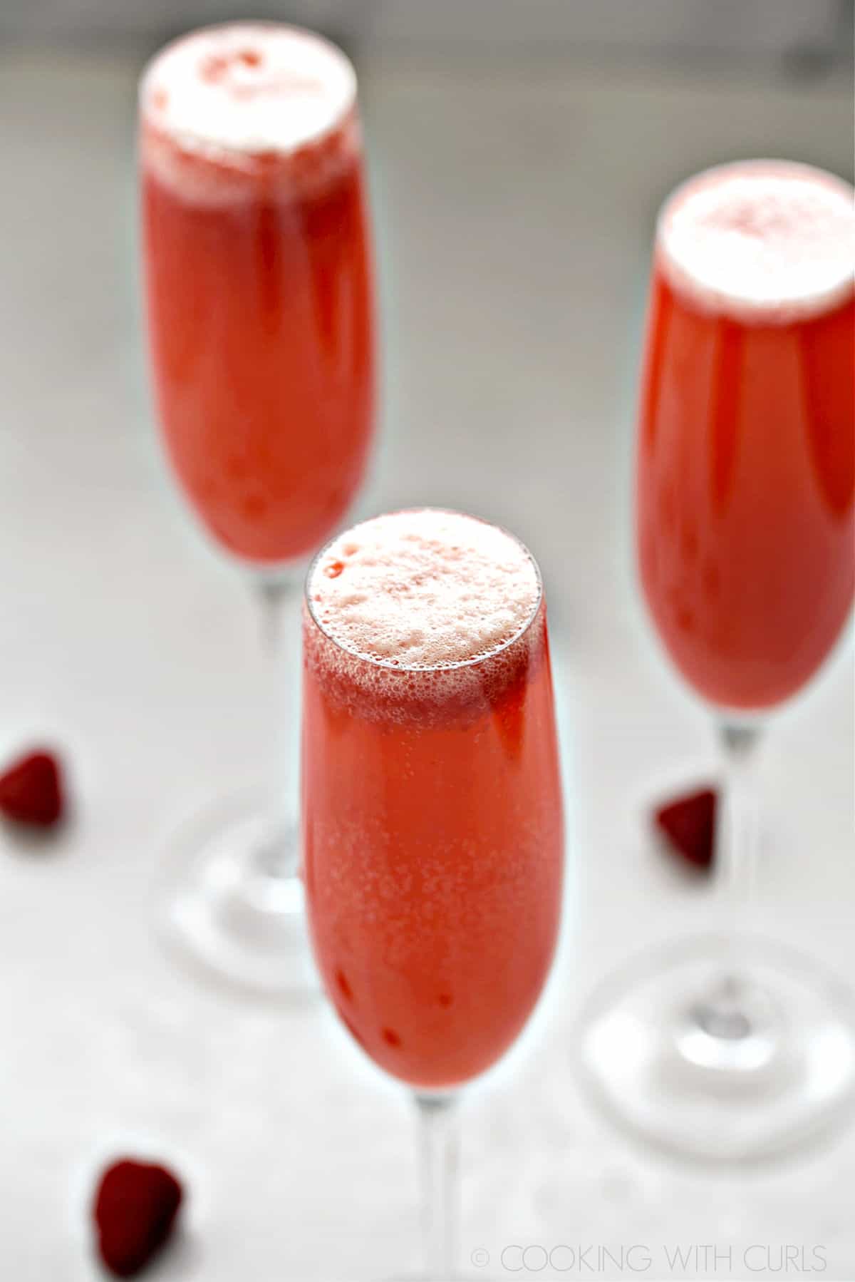 Three Raspberry Bellini cocktails in champagne flutes.