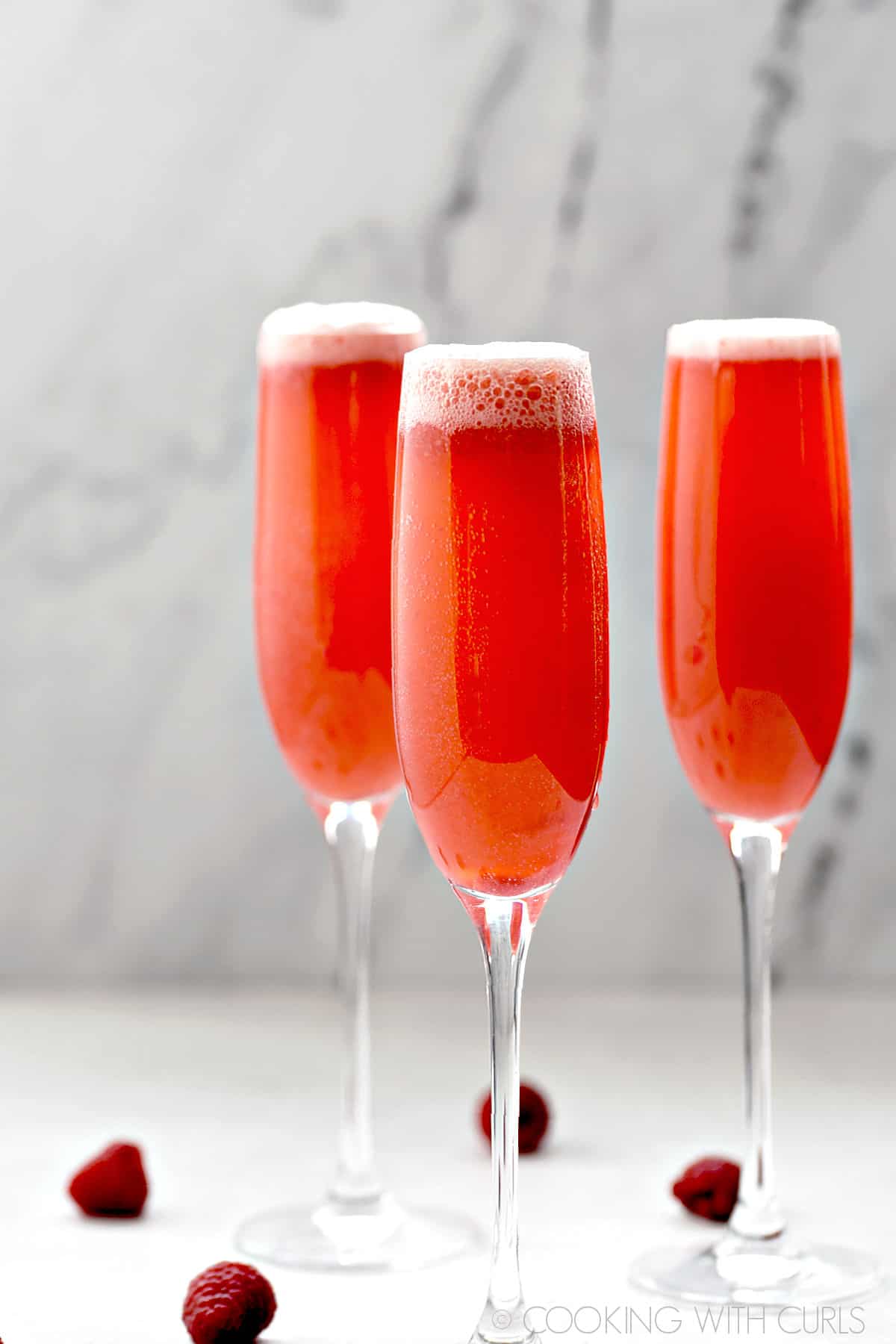 Three Raspberry Bellini Cocktails in champagne flutes.