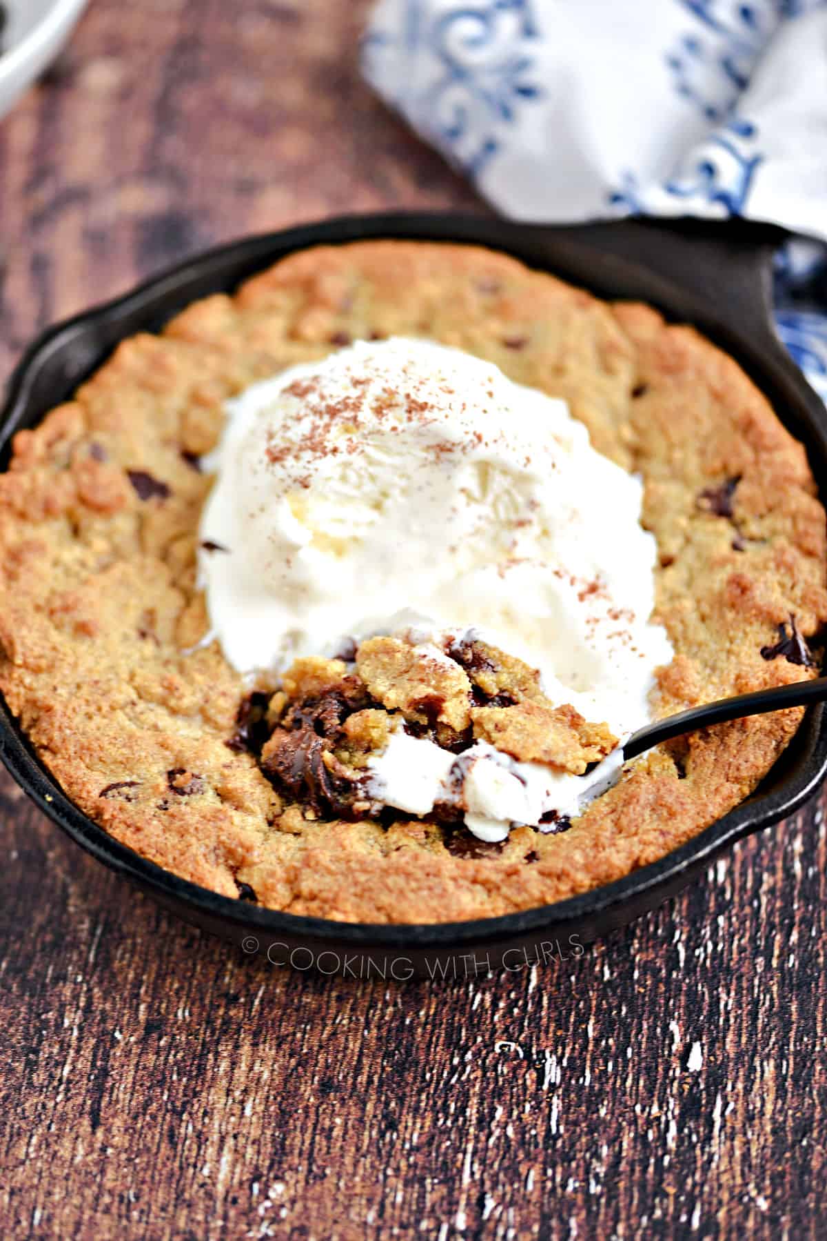 Warm, gooey Chocolate Chip Cookie for Two in a mini skillet topped with vanilla ice cream. 