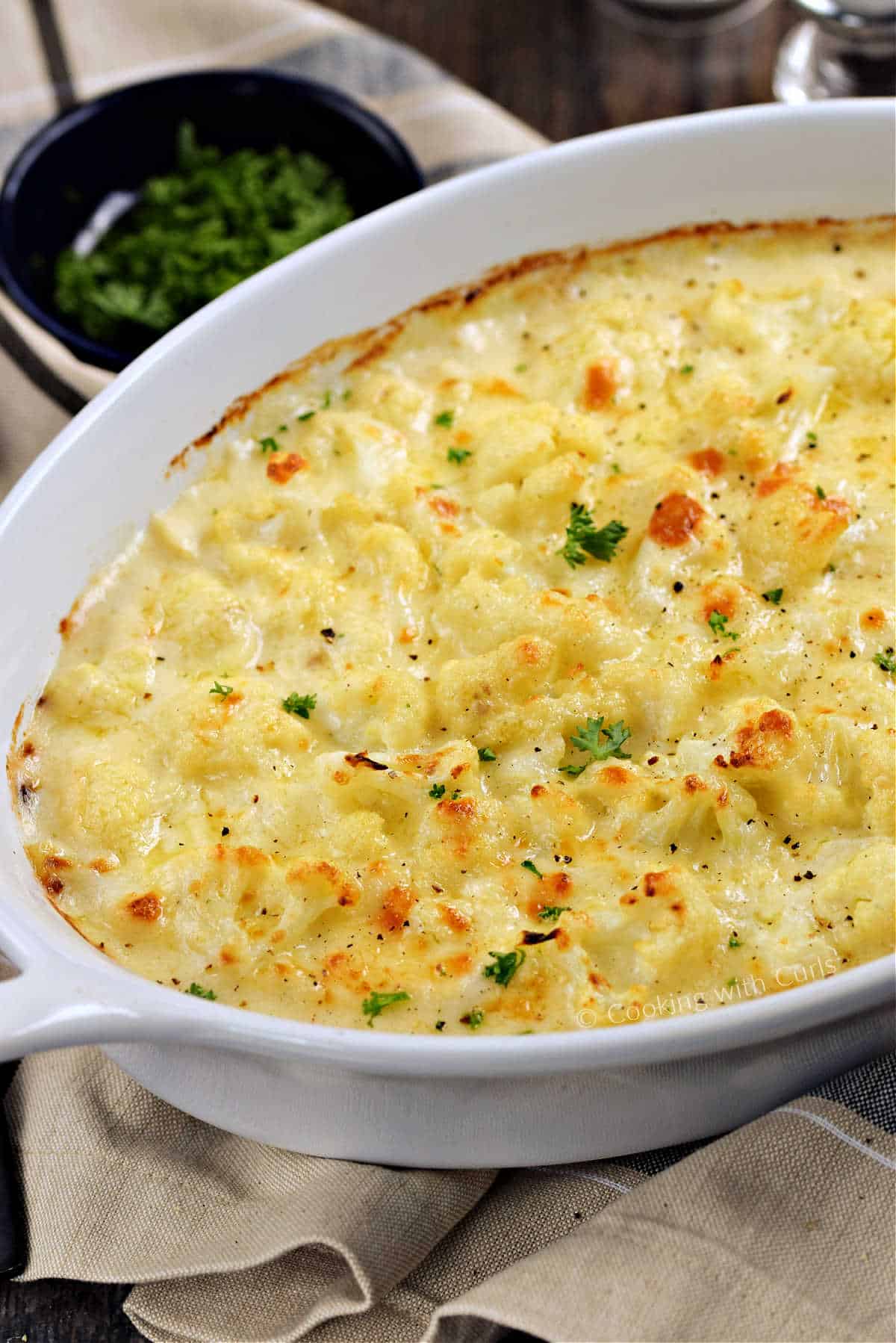 Cauliflower in cheese sauce baked in an oval baking dish.