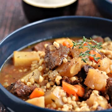 Instant Pot Beef and Barley Stew with potatoes and carrots in a blue bowl.