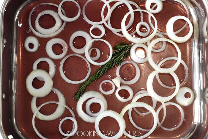 Wine, water, stock, onion rings and rosemary in a roasting pan. 