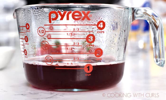 A large pyrex measuring cup with 1.13 cups of strawberry simple syrup. 