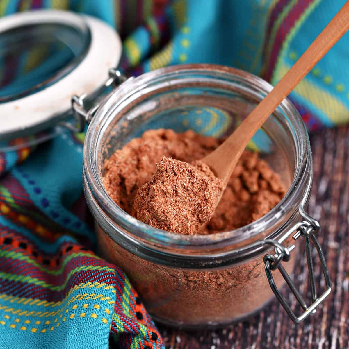 Mexican Seasoning Recipe in a small glass jar with a wooden spoon.