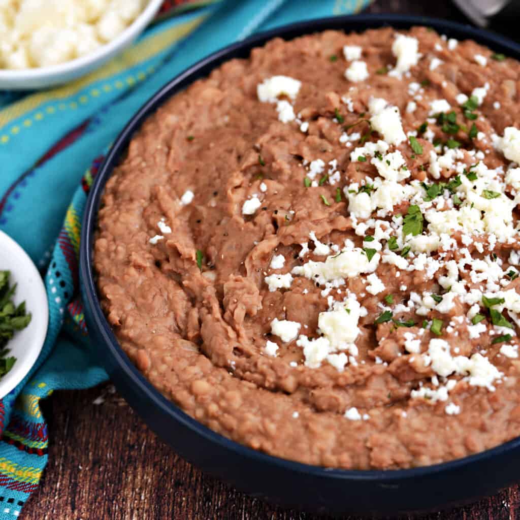 Creamy refried beans topped with crumbled cheese and chopped cilantro.