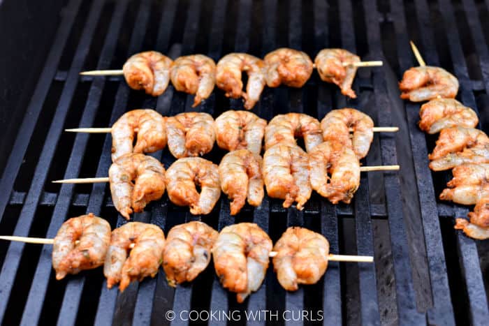 Five bamboo skewered shrimp on the grill. 