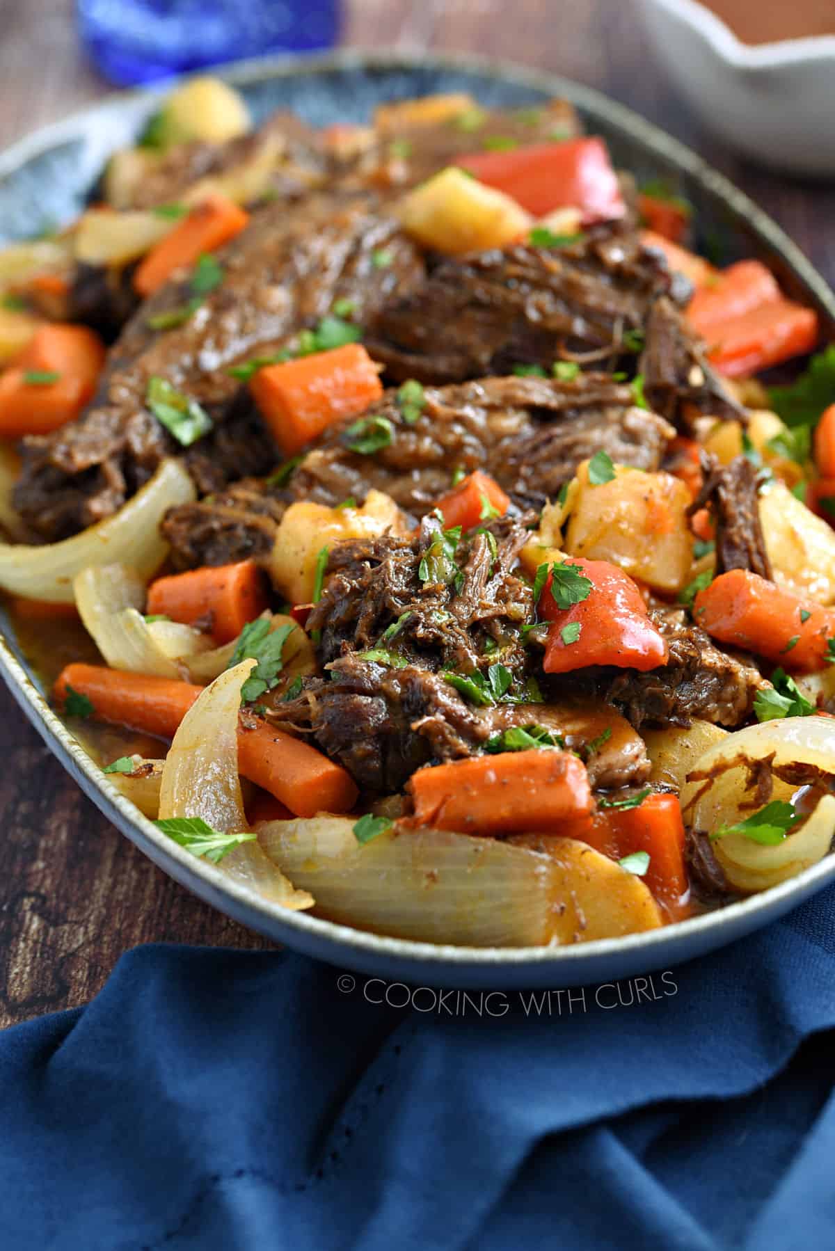 Pot roast, carrots, parsnips, bell pepper and onion wedges in a large platter garnished with chopped cilantro.