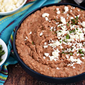 Creamy instant pot refried beans topped with crumbled cheese and chopped cilantro.