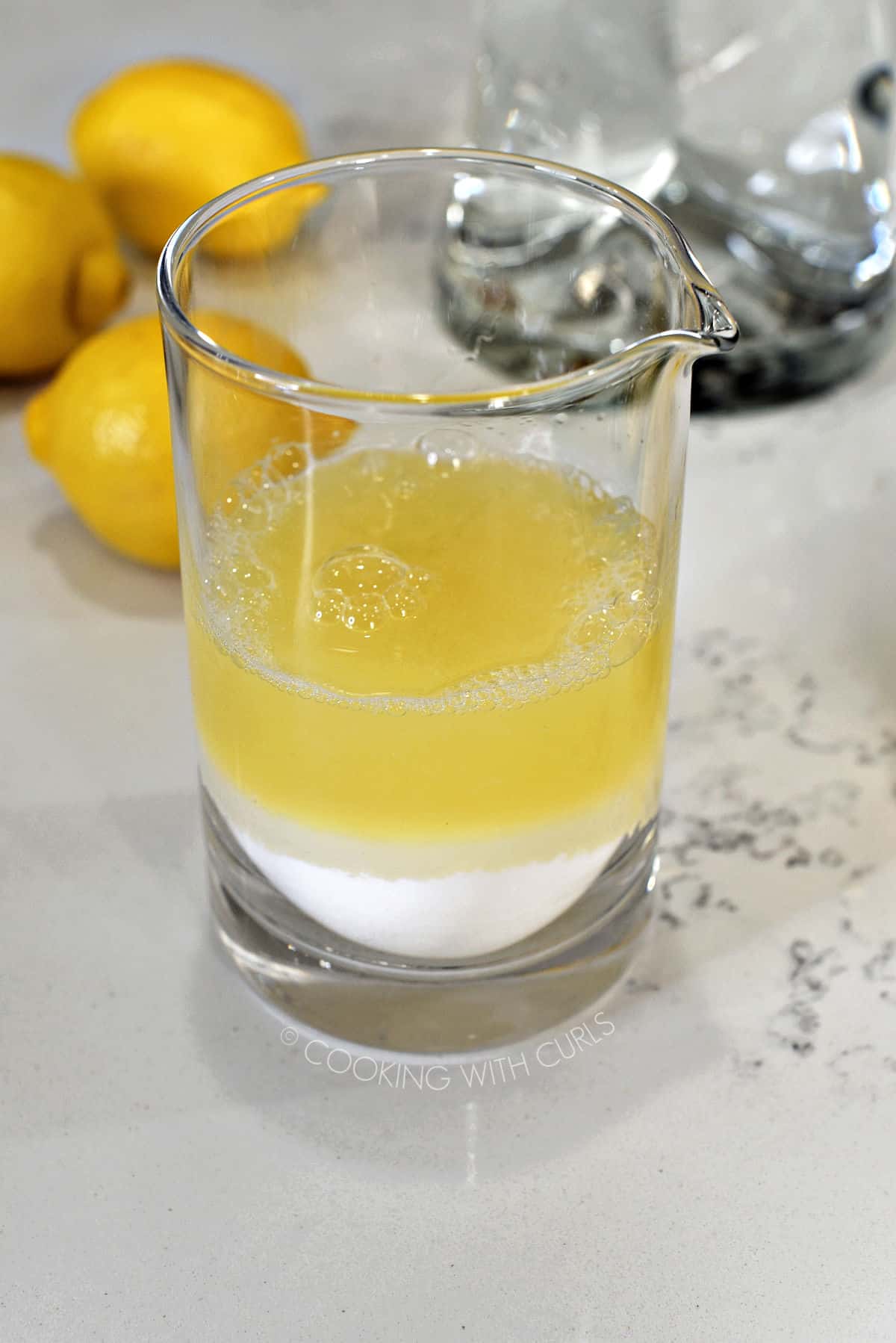 Lemon juice and sugar in a glass measuring cup. 