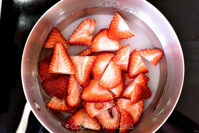 Sliced strawberries, water and sugar in a saucepan. 