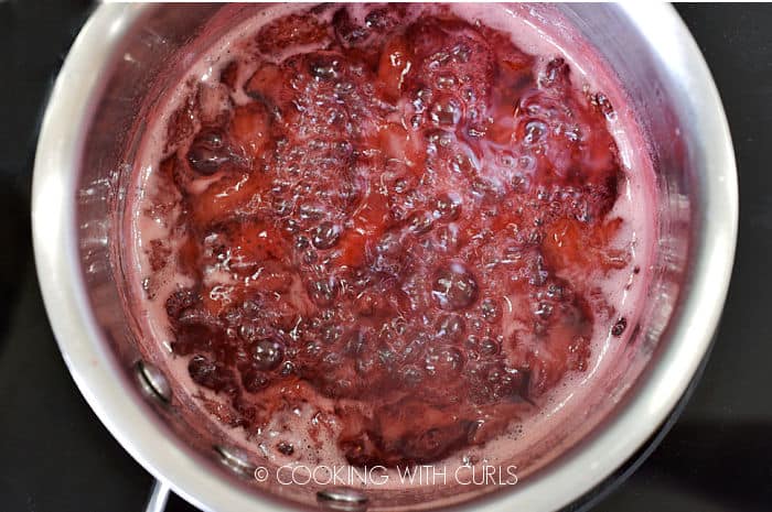 Strawberries, water and sugar boiling in a saucepan. 