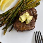 Air Fryer Steak and Asparagus topped with garlic butter on a white plate.