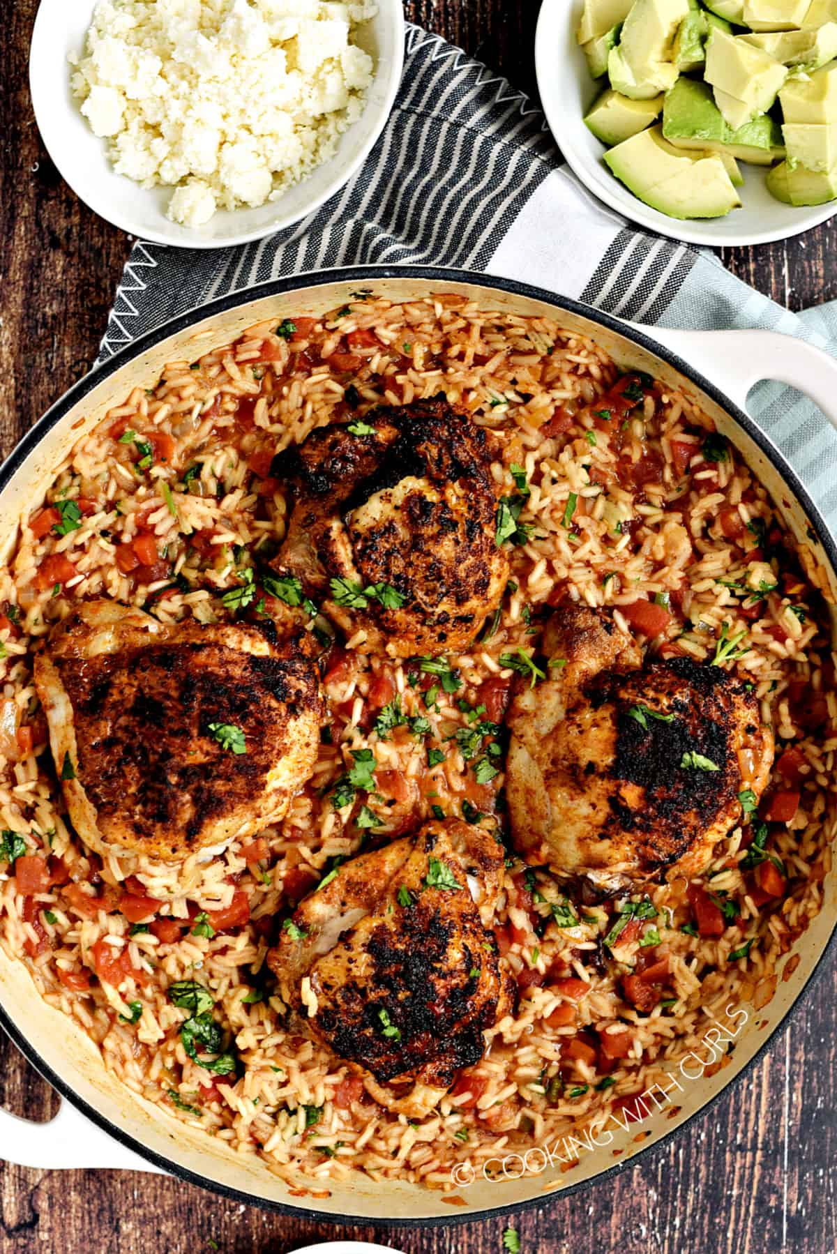 Mexican Arroz con Pollo with chicken thighs on a bed of rice in a white skillet.