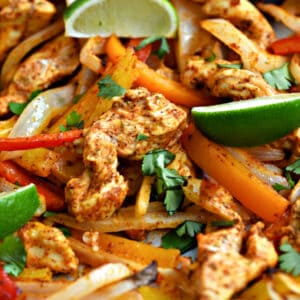 Strips of chicken, onion, red, orange and yellow bell peppers, and lime wedges.