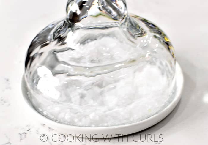 A margarita glass with the rim in a small plate filled with coarse salt. 