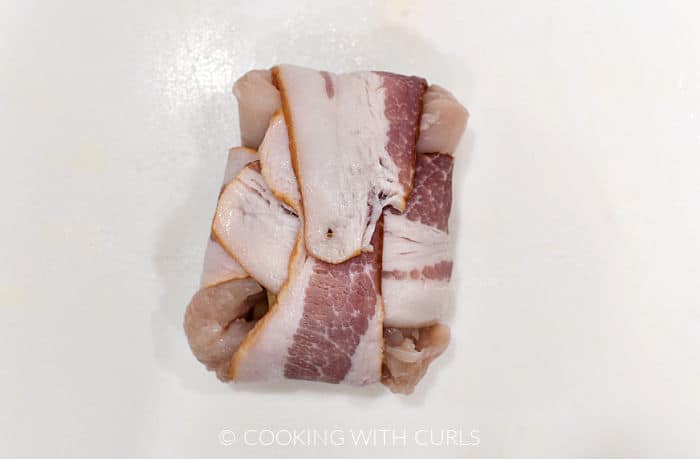 Bacon wrapped around chicken breast to create a small package. 