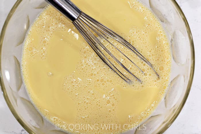 Heated cream and egg yolks whisked together in a large glass bowl. 