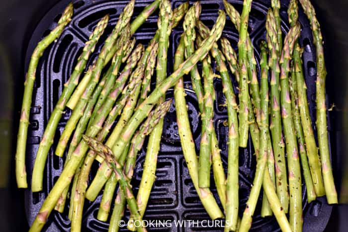 Raw asparagus in the air fryer basket. 