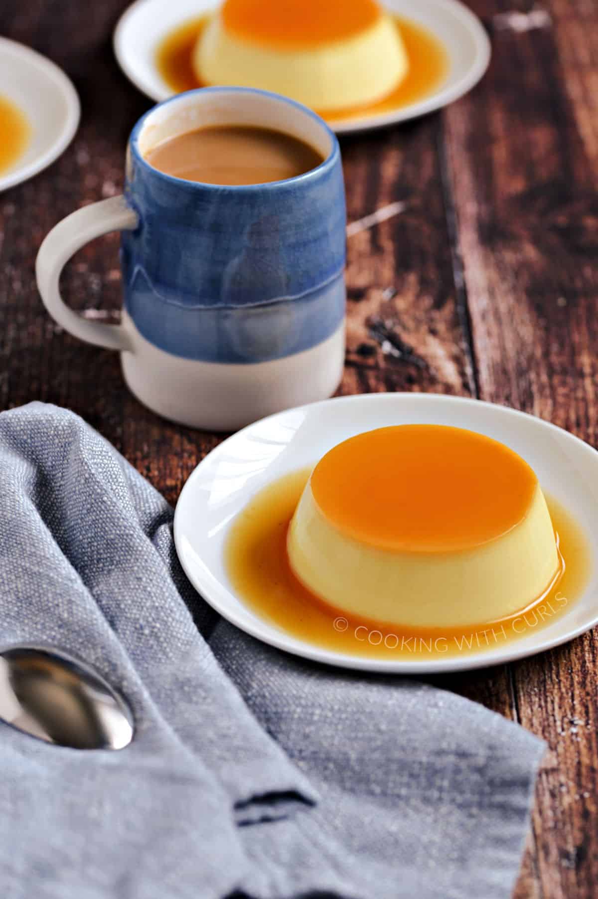 Three small white plates with caramel covered custard and a blue mug filled with coffee.