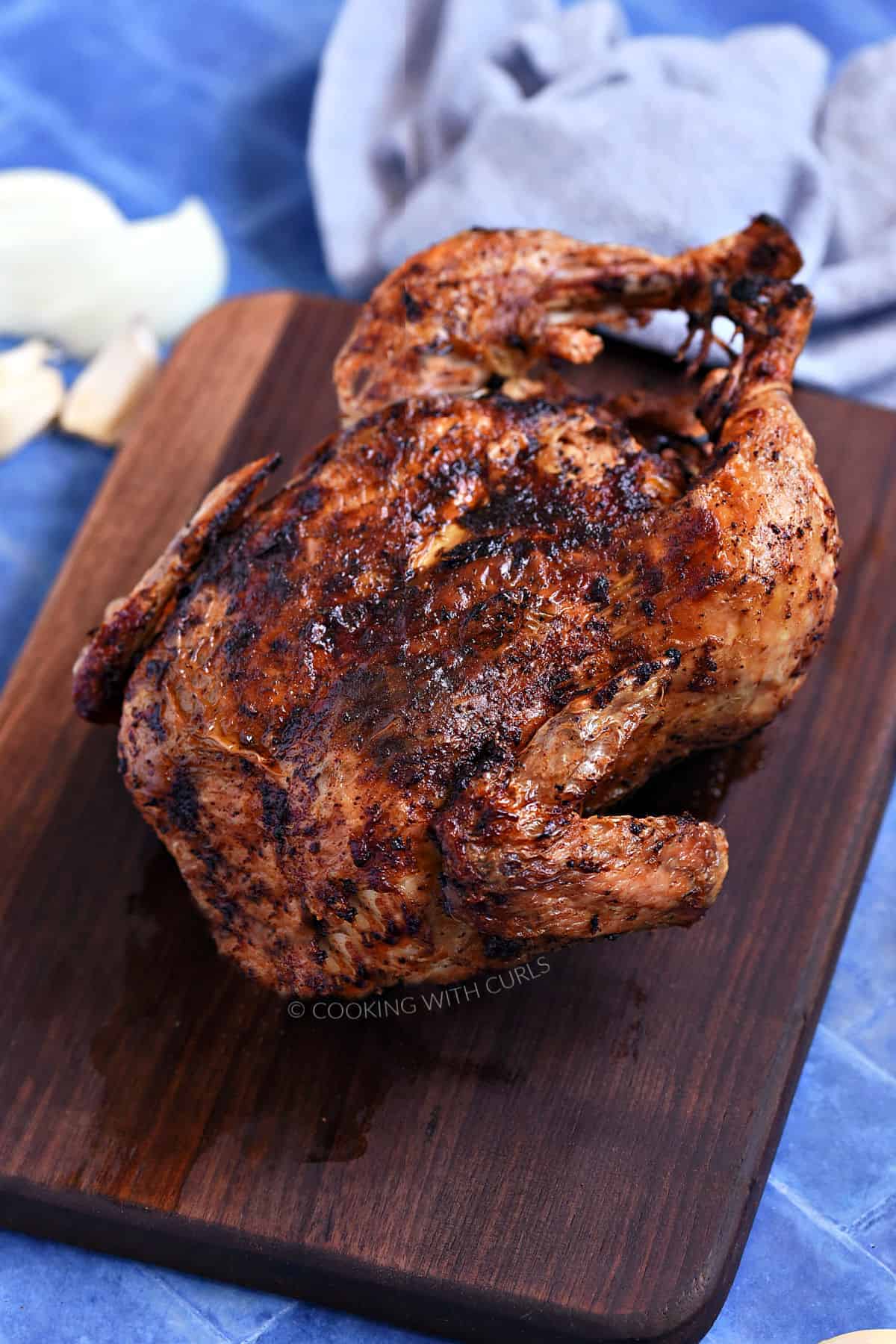 Whole roast chicken on a walnut board.