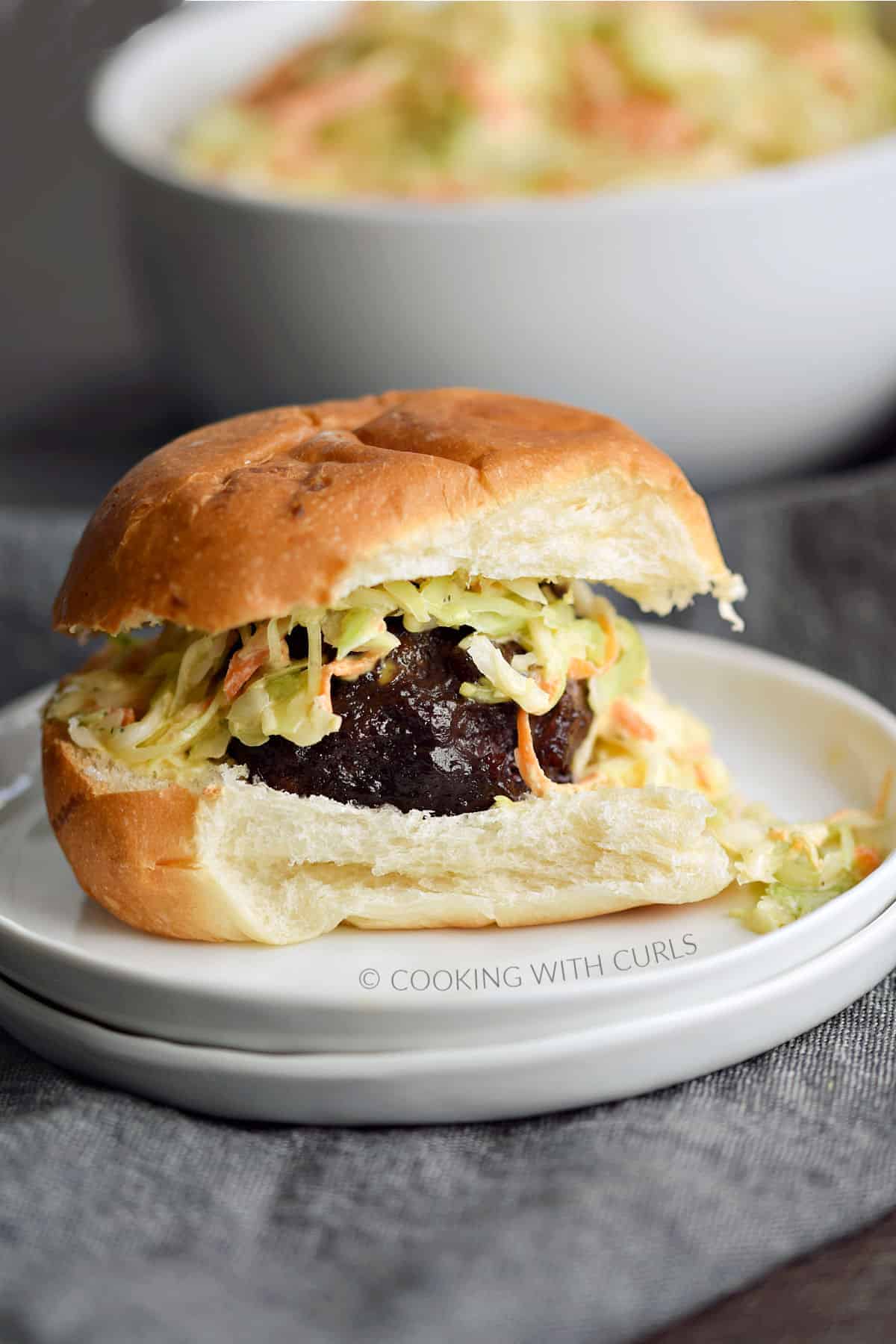 Meatball topped with coleslaw and a cocktail bun.