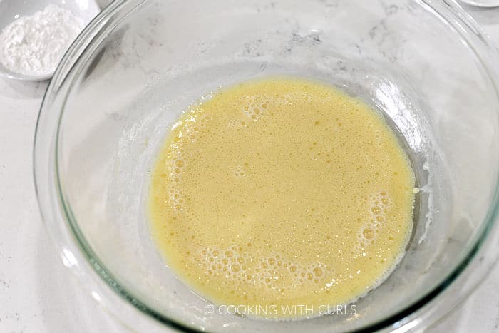 Egg, milk, and vanilla mixed in a large glass bowl. 