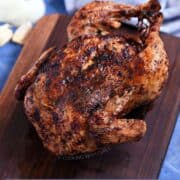 Whole roast chicken on a walnut board sitting on a blue tile background and title graphic across the top.