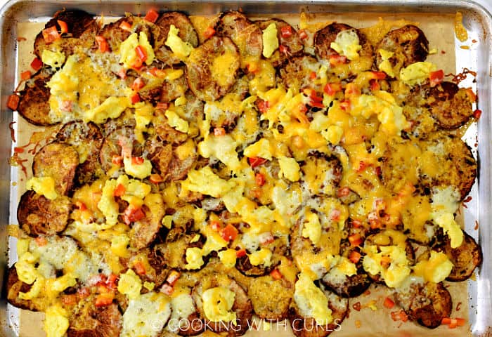Baked breakfast nachos on a parchment lined baking sheet. 