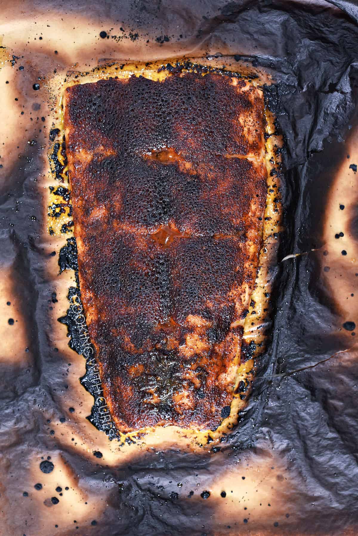 Broiled spice rubbed salmon filet on burnt parchment paper. 