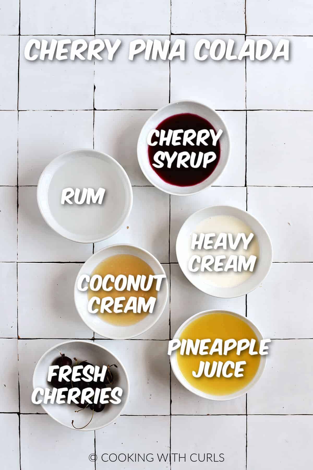 Cherry syrup, rum, cream, coconut cream, fresh cherries, and pineapple juice in small white bowls. 