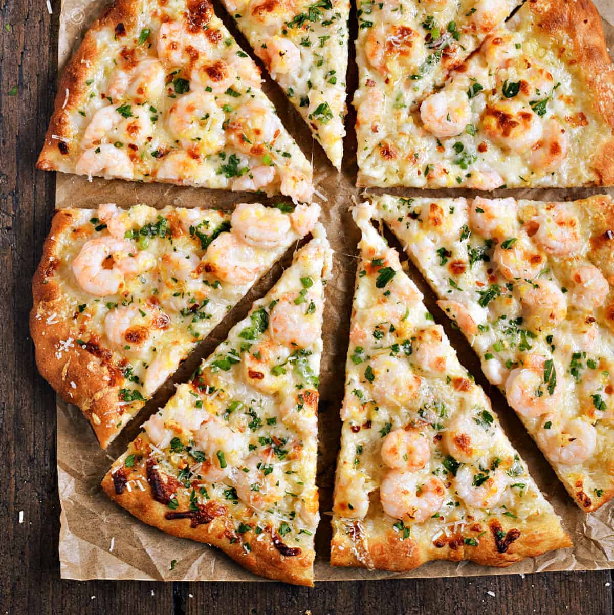 A pizza topped with shrimp, melted cheese and chopped parsley.