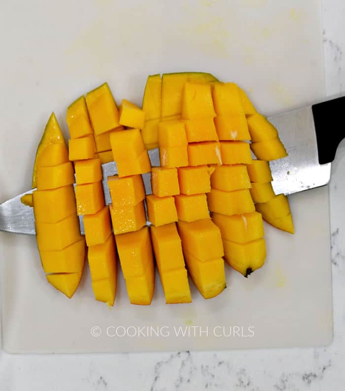 Fresh papaya cut into cubes with a chefs knife then cut away from the skin. 