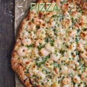 A pizza topped with shrimp, melted cheese and chopped parsley with title graphic across the top.