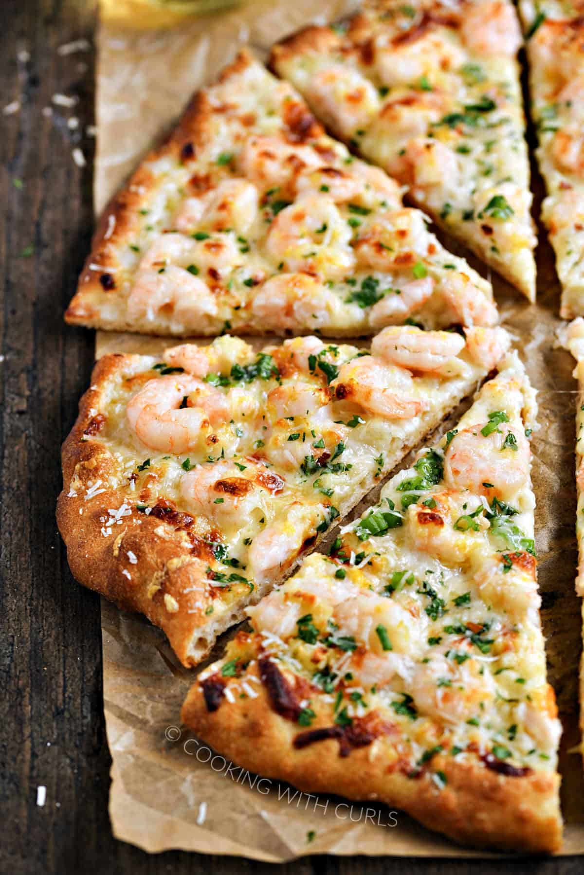 Half of a sliced shrimp pizza on a sheet of parchment paper.