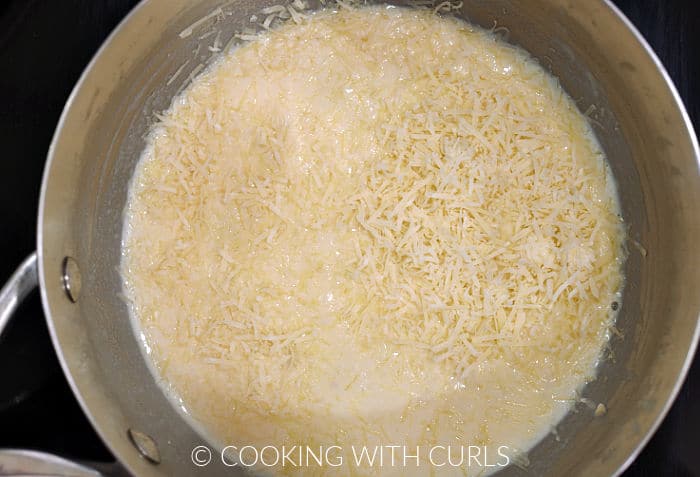 Shredded cheese added to the roux in a saucepan. 