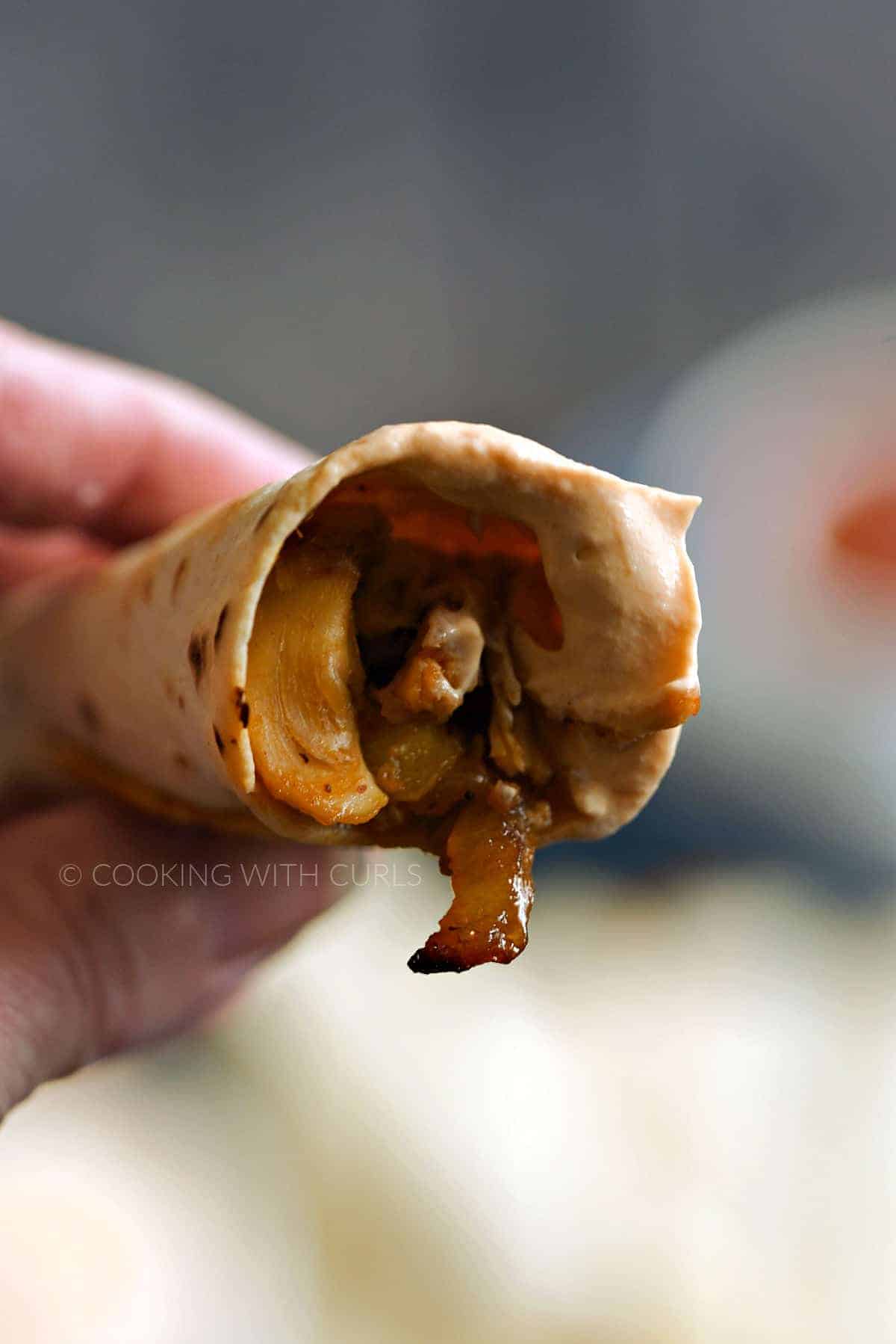 The inside of a baked Peachy Chicken Taquito dipped in creamy adobo sauce. 