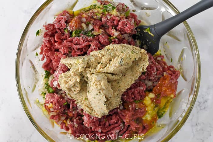 Breadcrumb mixture added to the meat mixture in a large bowl.