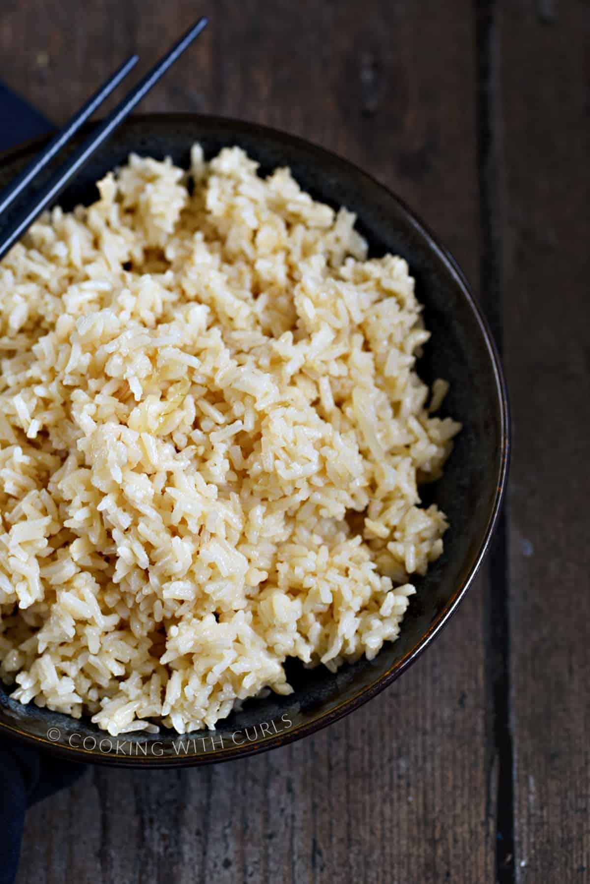 Garlic Rice in a blue bowl with blue chopsticks on the edge.