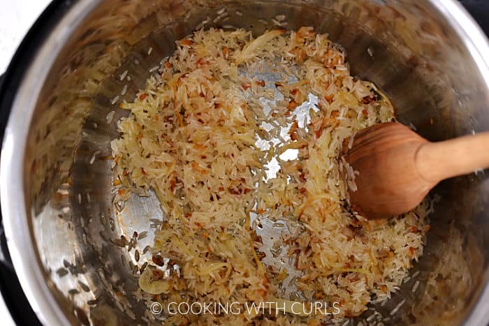 Rice stirred into the caramelized garlic and onions with a wooden spoon. 