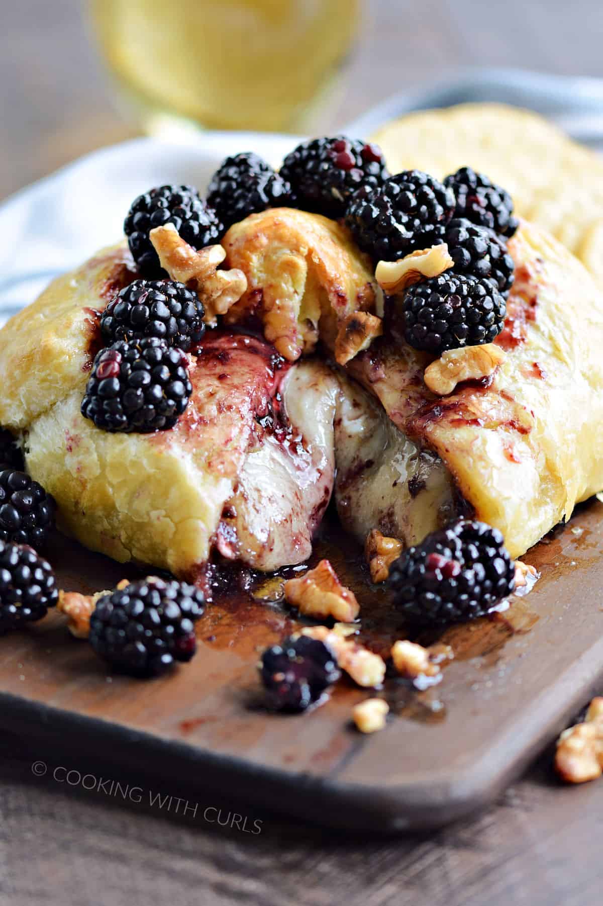 Melted cheese surrounded by puff pastry topped with blackberries and walnuts.
