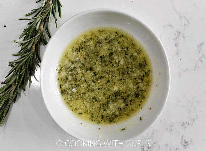 Garlic, chopped rosemary, and butter mixed together in a small bowl. 