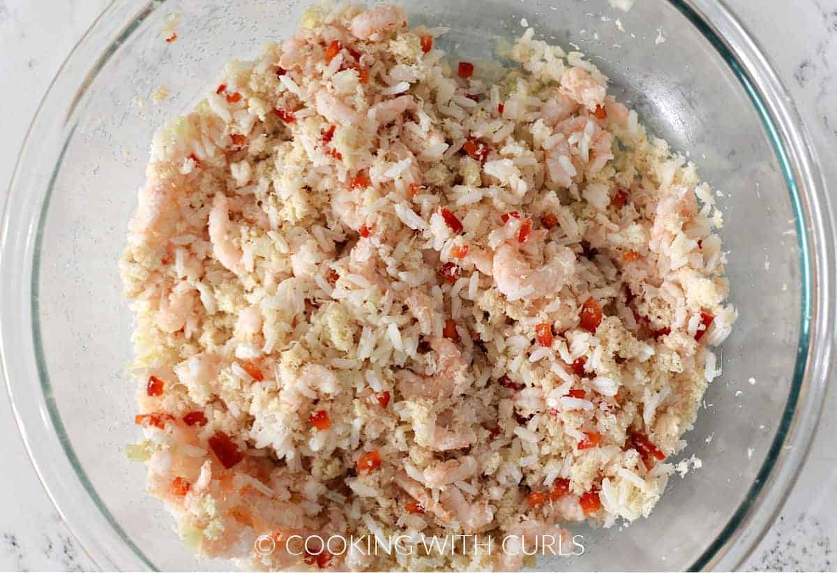 Shrimp, crab, rice, peppers, and onion mixed together in a medium sized bowl. 