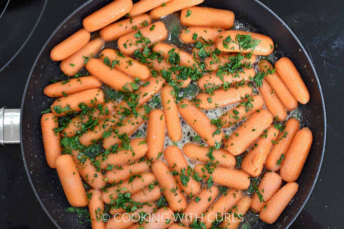 Baby carrots, butter, brown sugar, honey, and chopped parsley in a large skillet. 