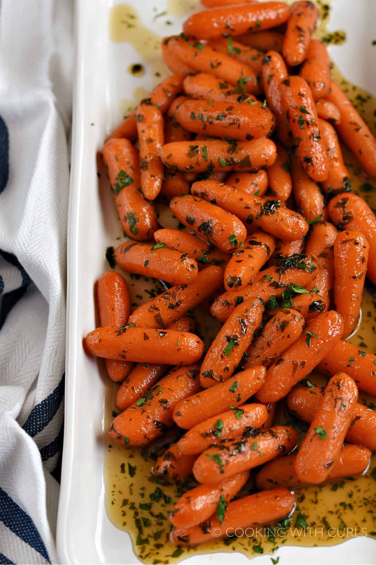 Honey Glazed Carrots topped with chopped parsley on a white platter. 
