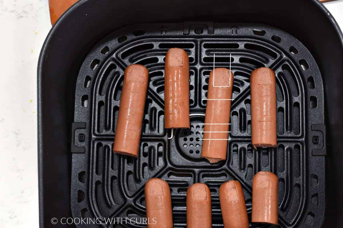 Hot dogs cut to look like fingers and toes in an air fryer basket.